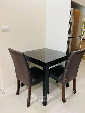 Cozy dining nook with sleek black table and modern chairs, adjacent to stainless steel fridge in stylish kitchen.