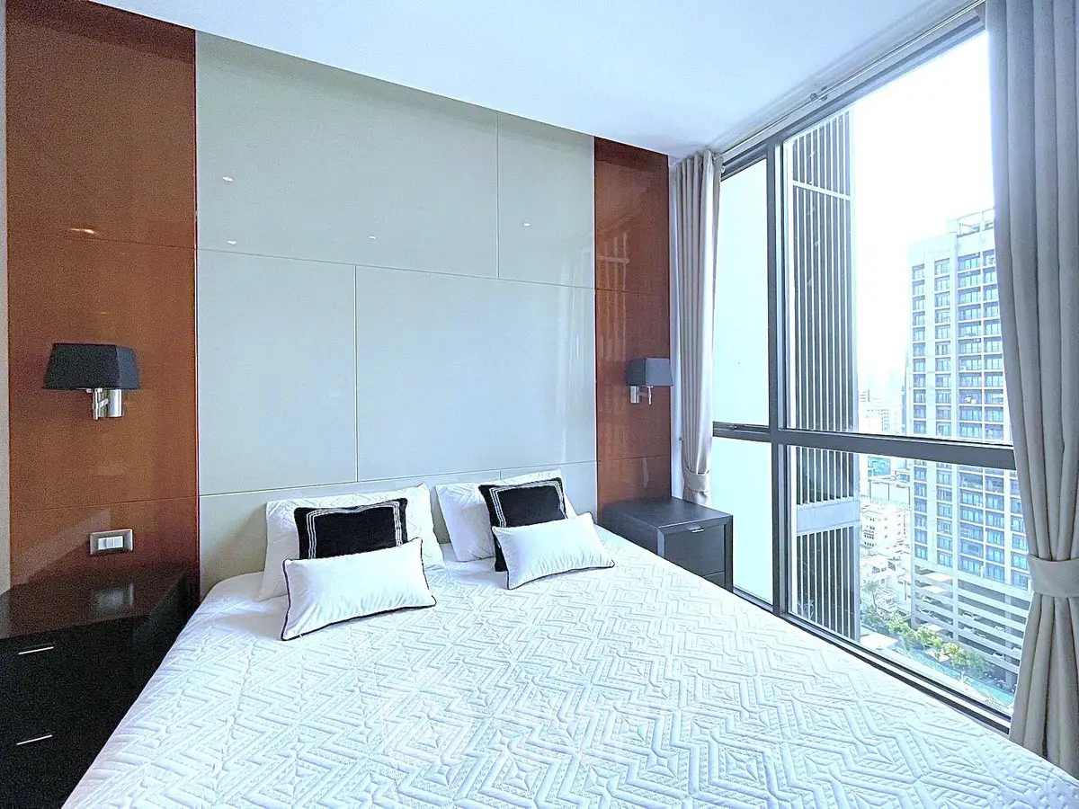 Luxurious bedroom with large windows offering stunning city views in a modern high-rise apartment.