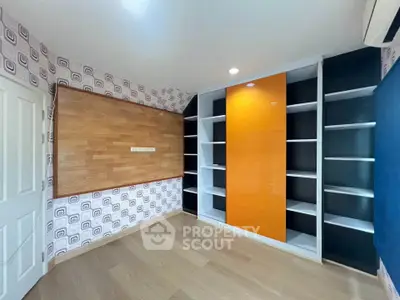 Modern study room with built-in shelves and vibrant orange accent panel