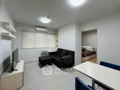 Modern living room with sleek furniture and open layout leading to a cozy bedroom.