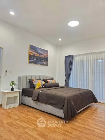 Spacious bedroom with elegant decor and large window for natural light.