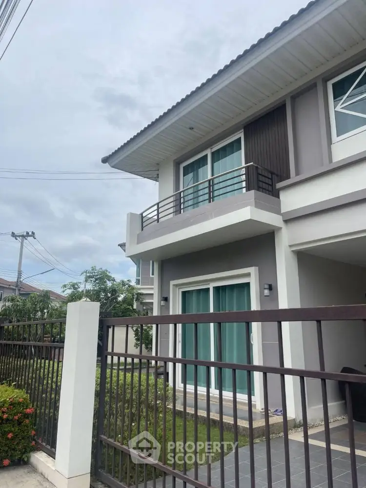 Modern two-story house with balcony and garden in a serene neighborhood.