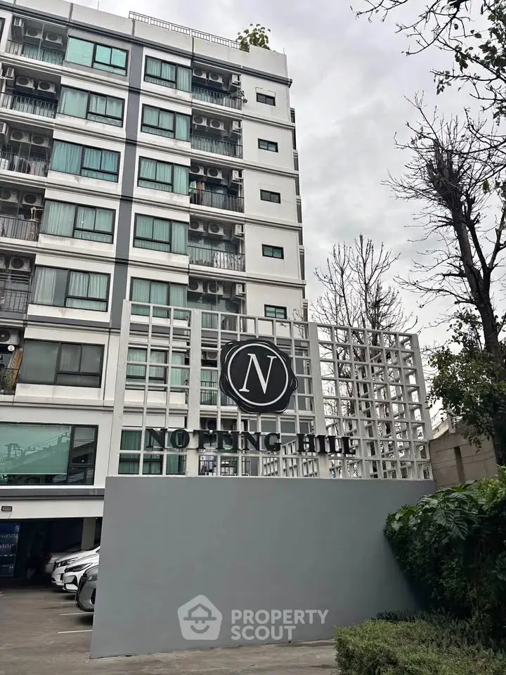 Modern apartment building with stylish facade and logo, showcasing urban living.