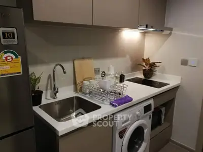 Modern kitchen with sleek appliances and compact design, featuring a washing machine and electric stove.