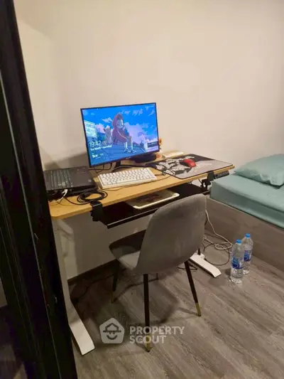 Cozy study area with modern desk, chair, and computer setup in a compact room.