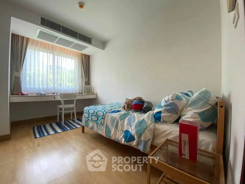 Cozy bedroom with modern decor and large window offering natural light.