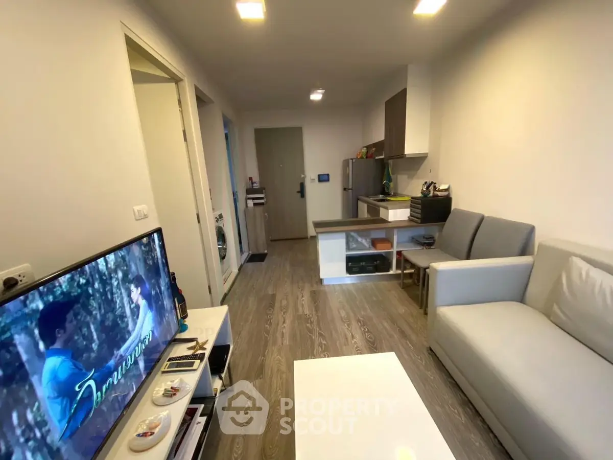 Modern living room with sleek furniture and open kitchen layout in a cozy apartment.