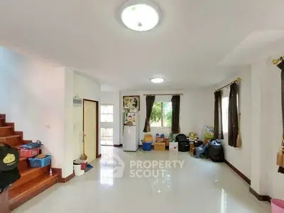 Spacious living room with natural light and staircase, ideal for family gatherings.