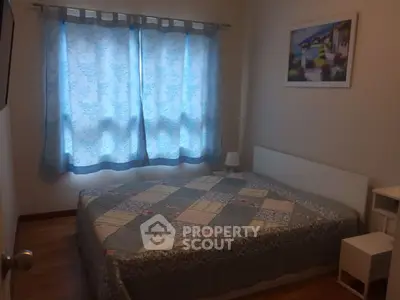 Cozy bedroom with patterned quilt and blue curtains, perfect for relaxation.