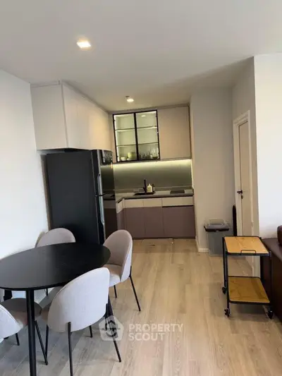 Modern kitchen with sleek design and dining area in open layout apartment.