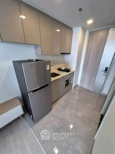 Modern kitchen with sleek cabinets and stainless steel fridge in a compact apartment.