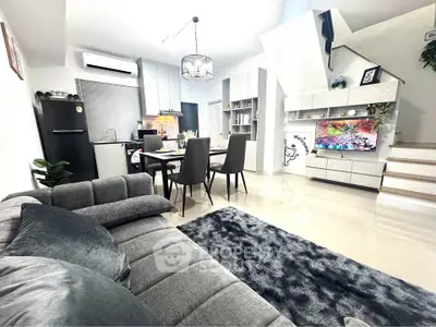 Modern open-plan living room with sleek kitchen and stylish dining area, featuring contemporary furniture and decor.
