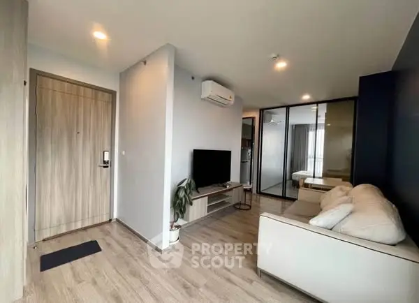 Modern living room with sleek design and wooden flooring, featuring a cozy sofa and wall-mounted TV.
