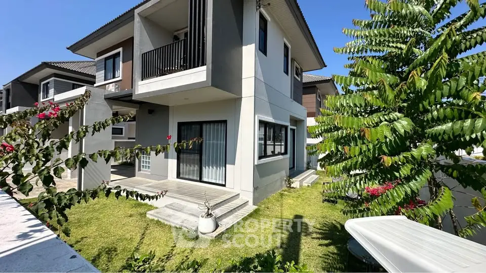 Modern two-story house with lush garden and balcony, perfect for family living.