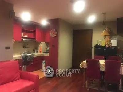 Cozy living room with red accents and open kitchen layout, perfect for modern living.