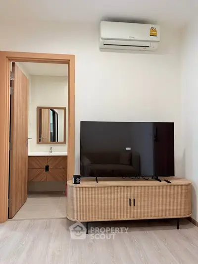 Modern living room with TV and air conditioning, adjacent to a stylish bathroom.