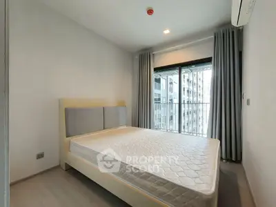Modern bedroom with large window and city view, featuring a comfortable bed and sleek design.