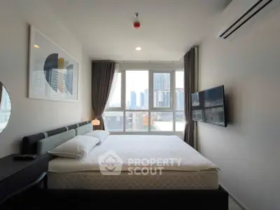 Modern bedroom with city view, featuring a wall-mounted TV and stylish decor.