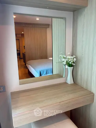 Modern bedroom with stylish wooden vanity and mirror, featuring elegant decor and cozy ambiance.