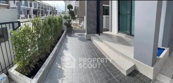 Modern residential entrance with sleek tiled walkway and greenery