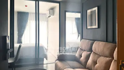 Modern apartment interior with cozy living room and stylish bedroom separated by glass doors.