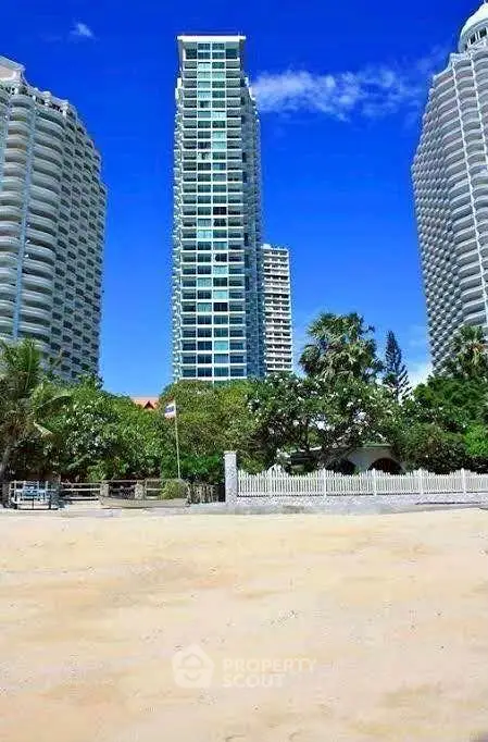 Stunning beachfront high-rise with lush greenery and clear blue skies.