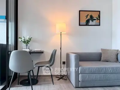 Modern living room with sleek gray sofa, stylish dining set, and elegant floor lamp.