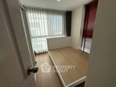 Cozy bedroom with large window and wooden flooring, perfect for natural light lovers.