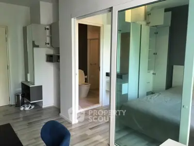 Modern apartment interior with glass partition, showcasing bedroom and bathroom.