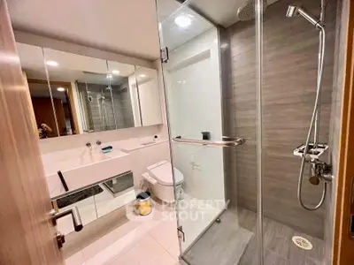 Modern bathroom with glass shower and sleek fixtures in luxury apartment.