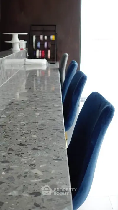 Modern kitchen with sleek granite countertop and stylish blue chairs