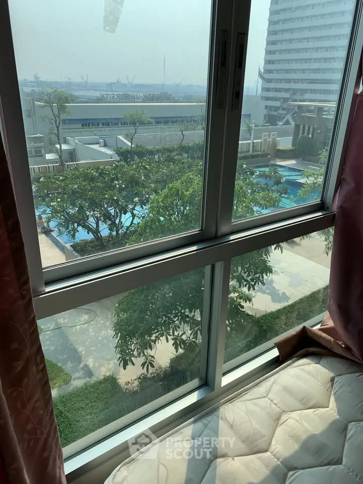 Stunning view from a high-rise apartment window overlooking a pool and cityscape.