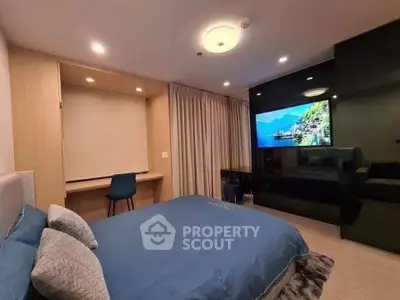 Modern bedroom with stylish decor, featuring a large TV and cozy workspace, perfect for relaxation and productivity.
