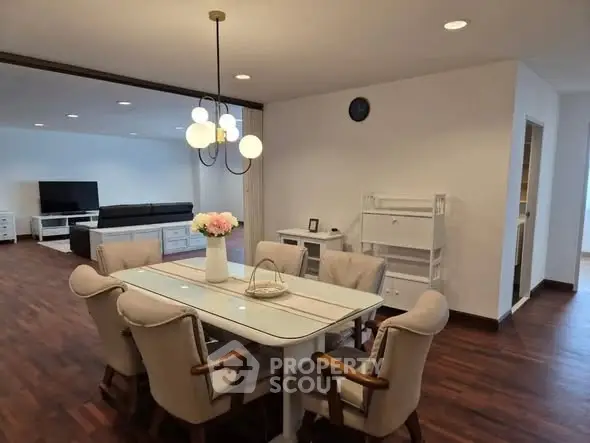 Spacious dining area with elegant lighting and wooden flooring in modern apartment.