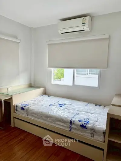 Cozy bedroom with single bed, air conditioning, and natural light from window.