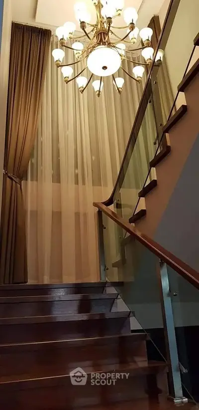 Elegant staircase with wooden steps and modern chandelier in luxury home