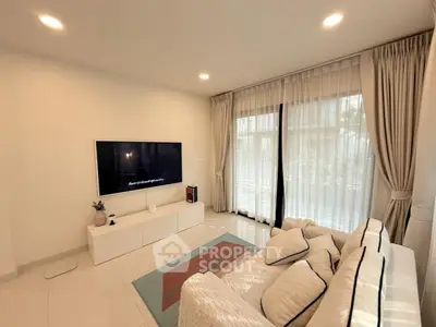 Modern living room with cozy sofa and large TV, featuring elegant curtains and bright lighting.