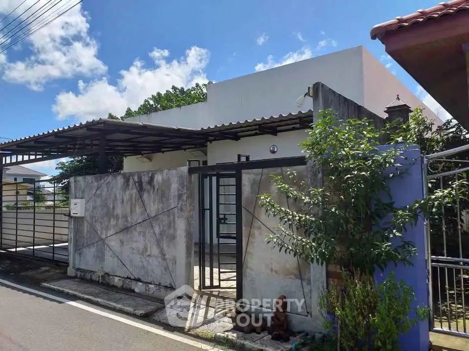 Charming modern house with gated entrance and spacious driveway under clear blue sky.