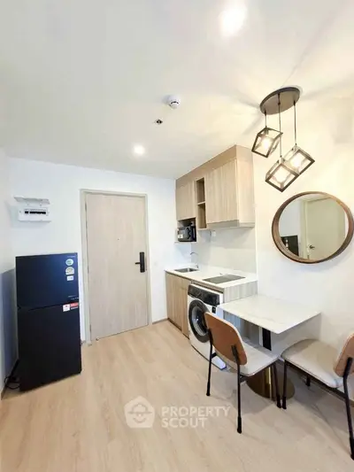 Modern compact kitchen with dining area, featuring washing machine and stylish lighting.