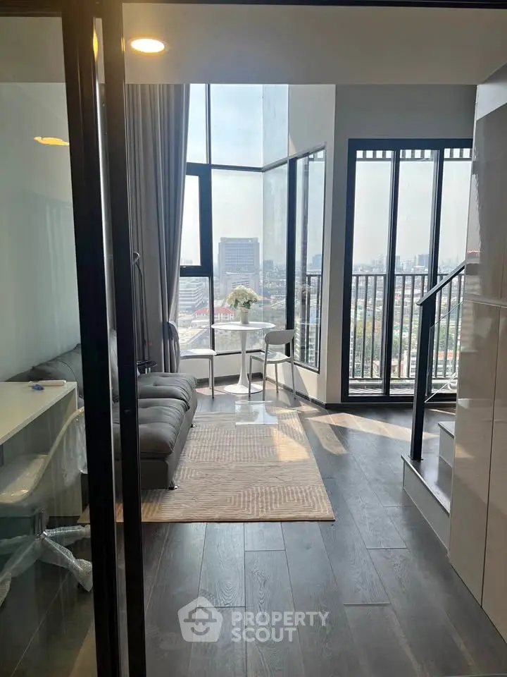 Modern living room with floor-to-ceiling windows and city view, featuring sleek furniture and elegant decor.
