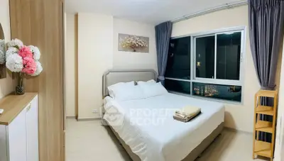 Cozy bedroom with modern decor and large window offering city views.