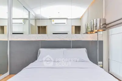 Modern bedroom with sleek design and mirrored accents, featuring a cozy bed and stylish lighting.