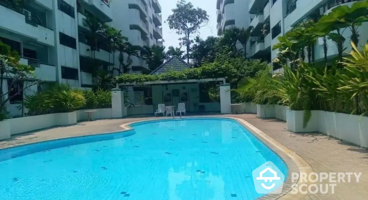 Luxurious residential pool surrounded by lush greenery and modern architecture.