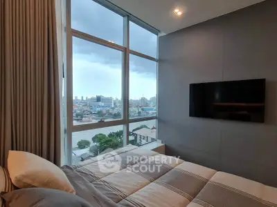 Luxurious bedroom with stunning city view through large windows, featuring modern decor and wall-mounted TV.
