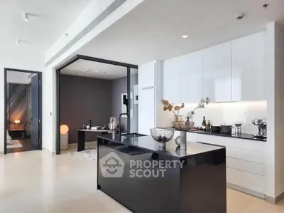 Modern kitchen with sleek black island and open layout, adjacent to stylish dining area.