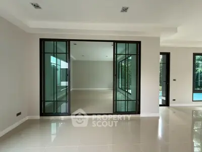 Spacious modern living room with large sliding glass doors and elegant tile flooring.