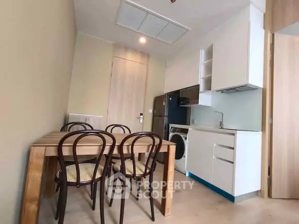 Modern kitchen with dining area featuring wooden table and chairs, compact appliances, and sleek cabinetry.