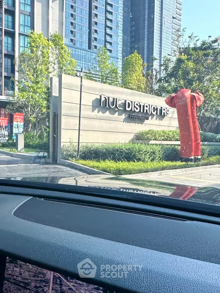 Modern apartment building entrance with lush landscaping and sleek signage
