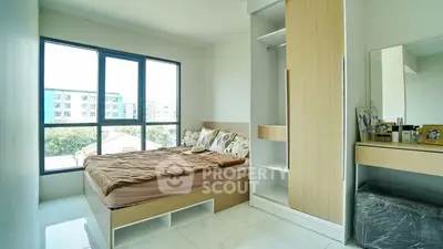 Modern bedroom with large window and built-in wardrobe in a bright apartment.