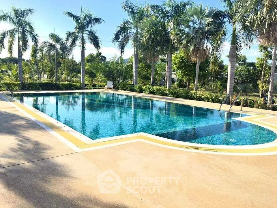 Luxurious outdoor pool surrounded by lush palm trees in a serene setting.